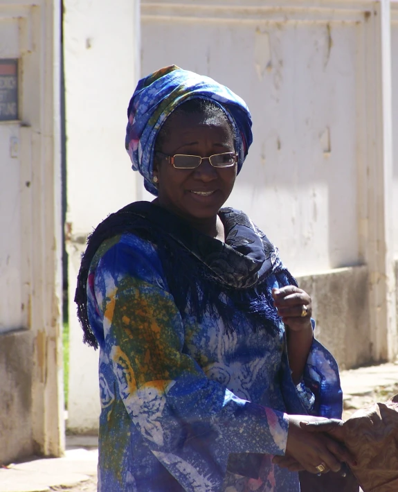 a woman is wearing a large scarf and sunglasses