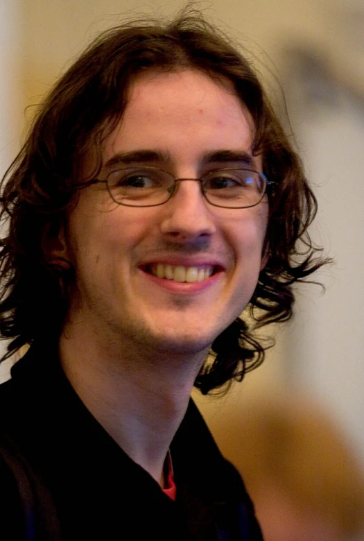 a man in glasses is smiling at the camera