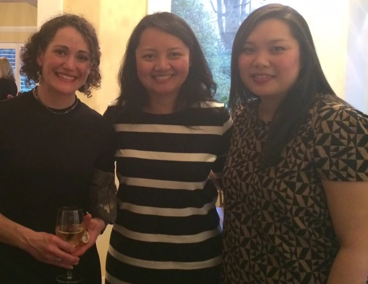 three women pose for a po while posing with one another