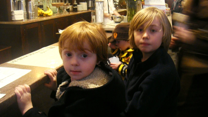 two young children sitting in front of a bar