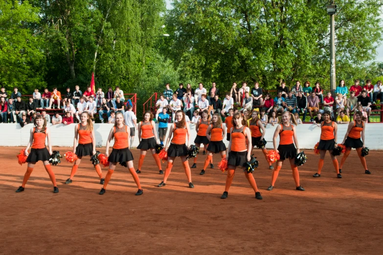 a large group of girls with orange shirts perform on a field