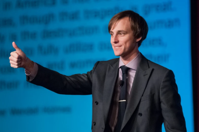 a man giving a speech in front of a screen