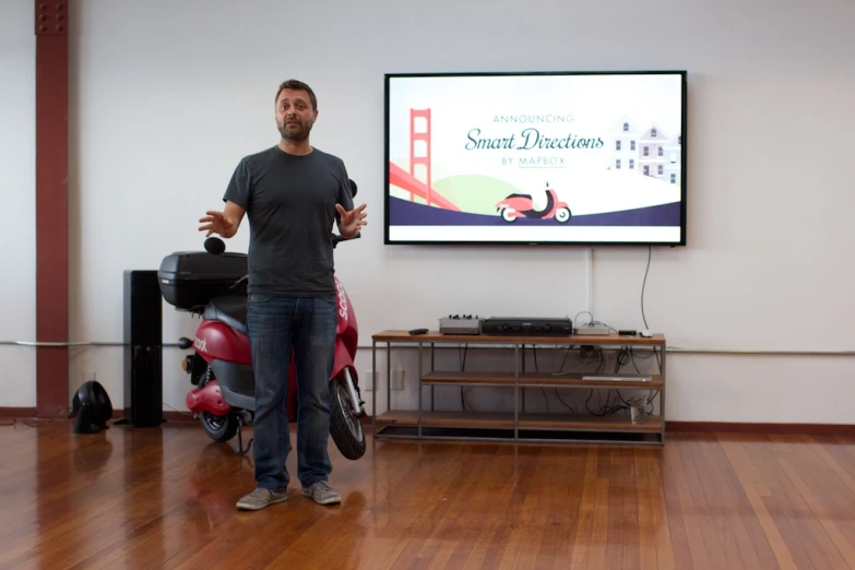 the man standing in front of a projector screen is presenting soing