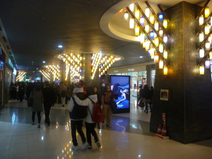 people walking in a hall filled with brightly lit lights