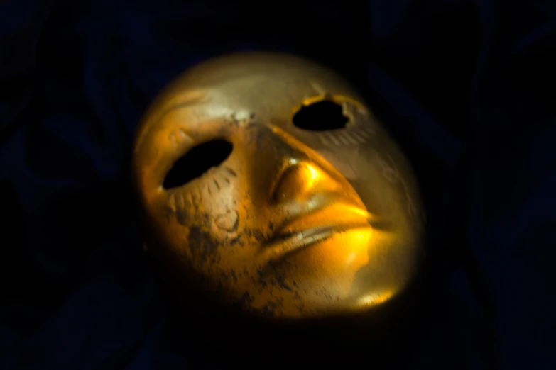 an old golden mask with a teary smile