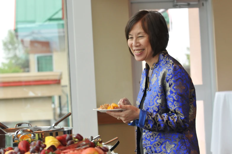 a woman holding a plate of food smiling for the camera