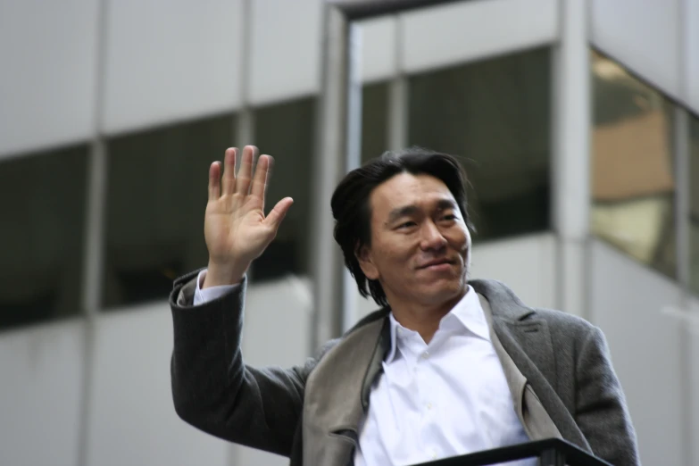 an asian businessman waves in the air with his hand