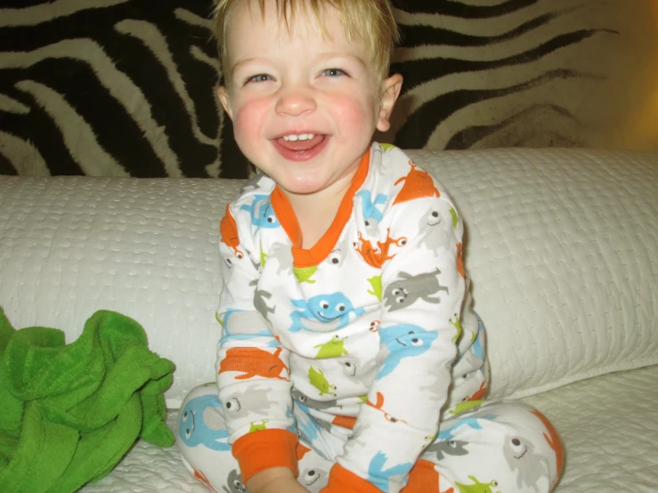 a young child sitting on a bed with a stuffed animal