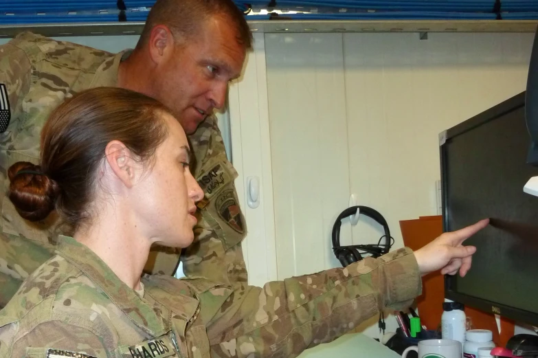 man in uniform looking at computer screen while woman points