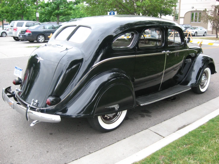 the vintage black car is parked on the side of the road