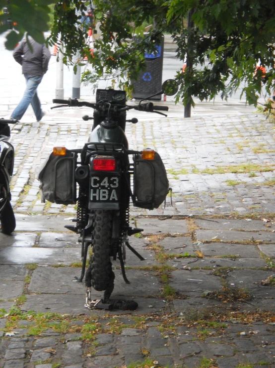 a parked motorcycle sitting on a sidewalk next to a tree