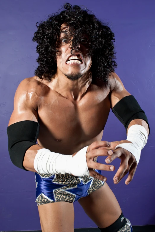 a man with long hair is sitting wearing wrestling gear