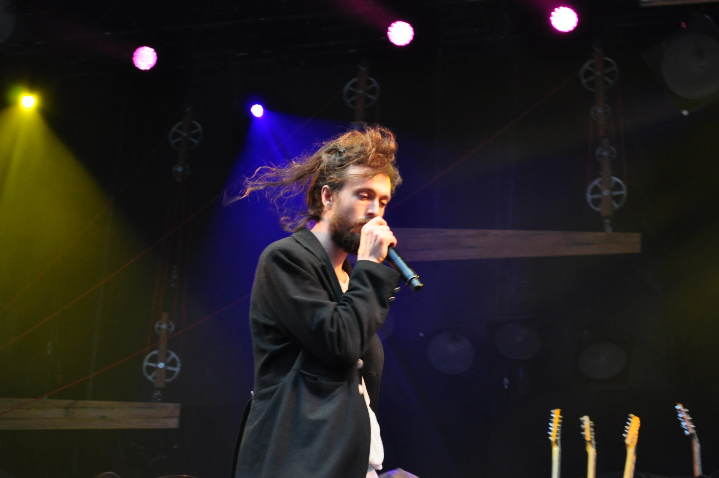 a young man on stage in front of purple light and an electric guitar