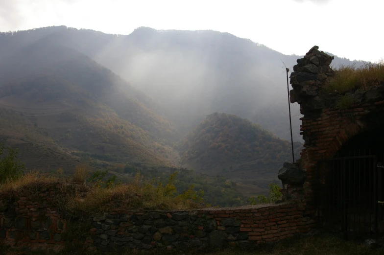 a tall mountain covered in mist on top of a hillside