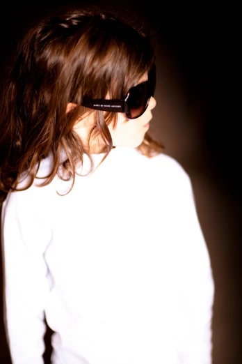 the young woman wears sunglasses and looks over her shoulder