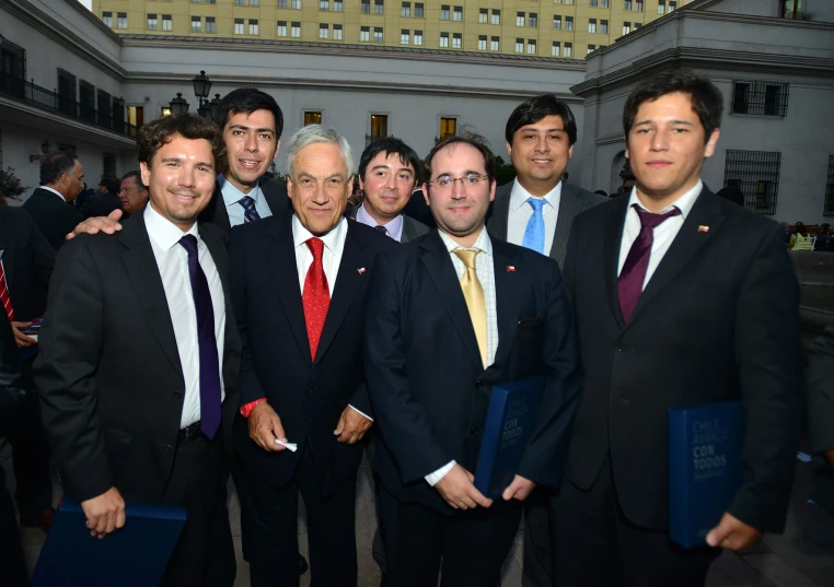 five men in suits standing together in front of some buildings