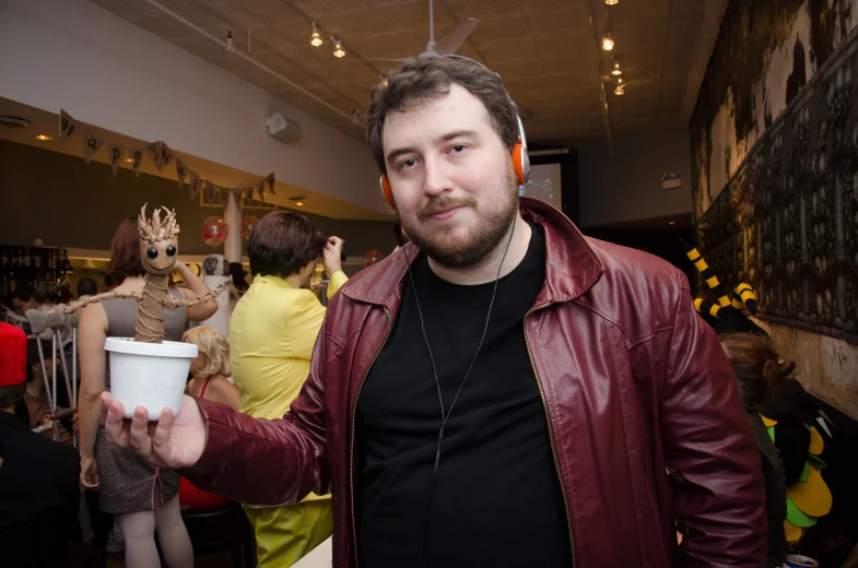 man in black shirt holding up a cup with headphones on