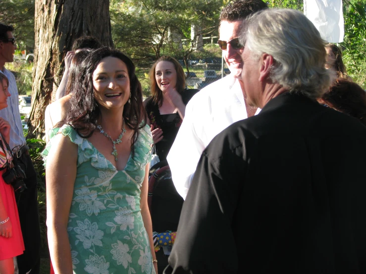 the woman is wearing a floral dress and smiling at another lady in a green dress