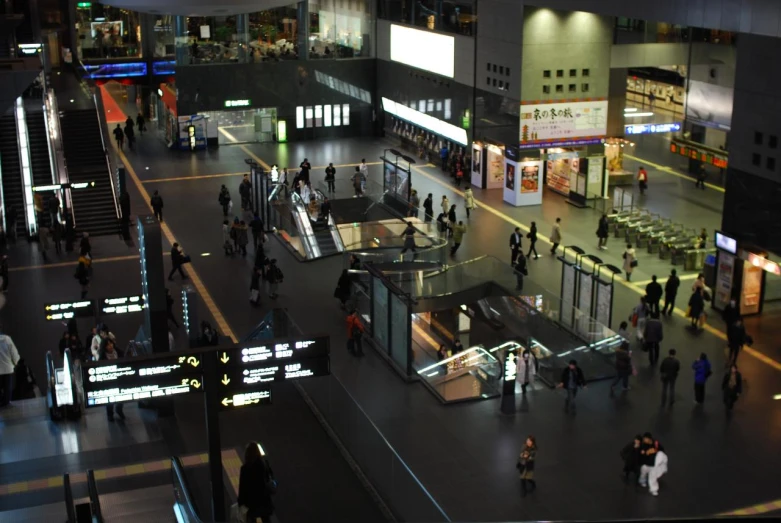 several people standing in a public area near stairs