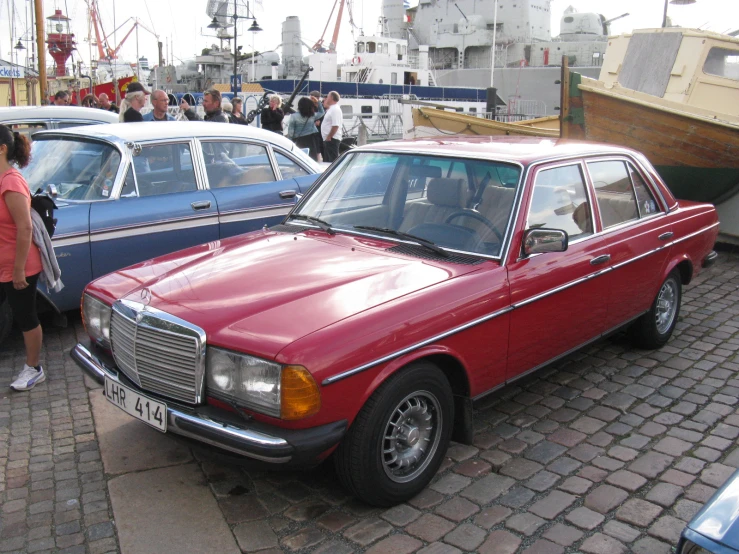 a group of older fashion cars sitting on the shore