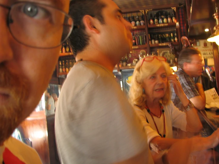 two old woman getting their hair combed by a man in the bar