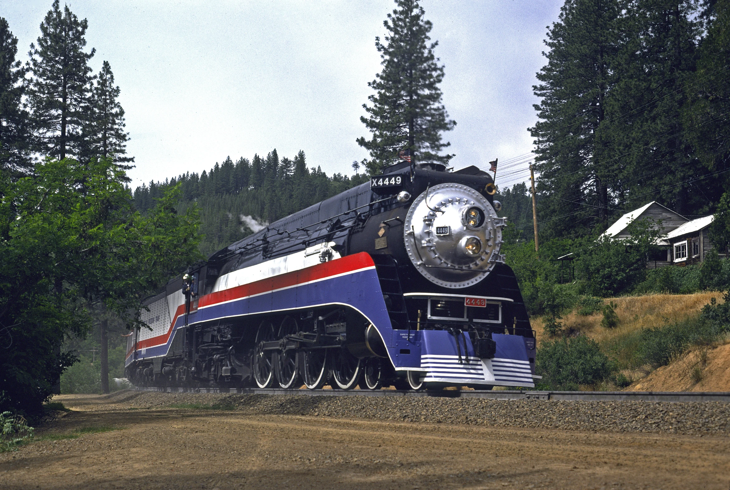 a colorful train traveling down tracks near trees