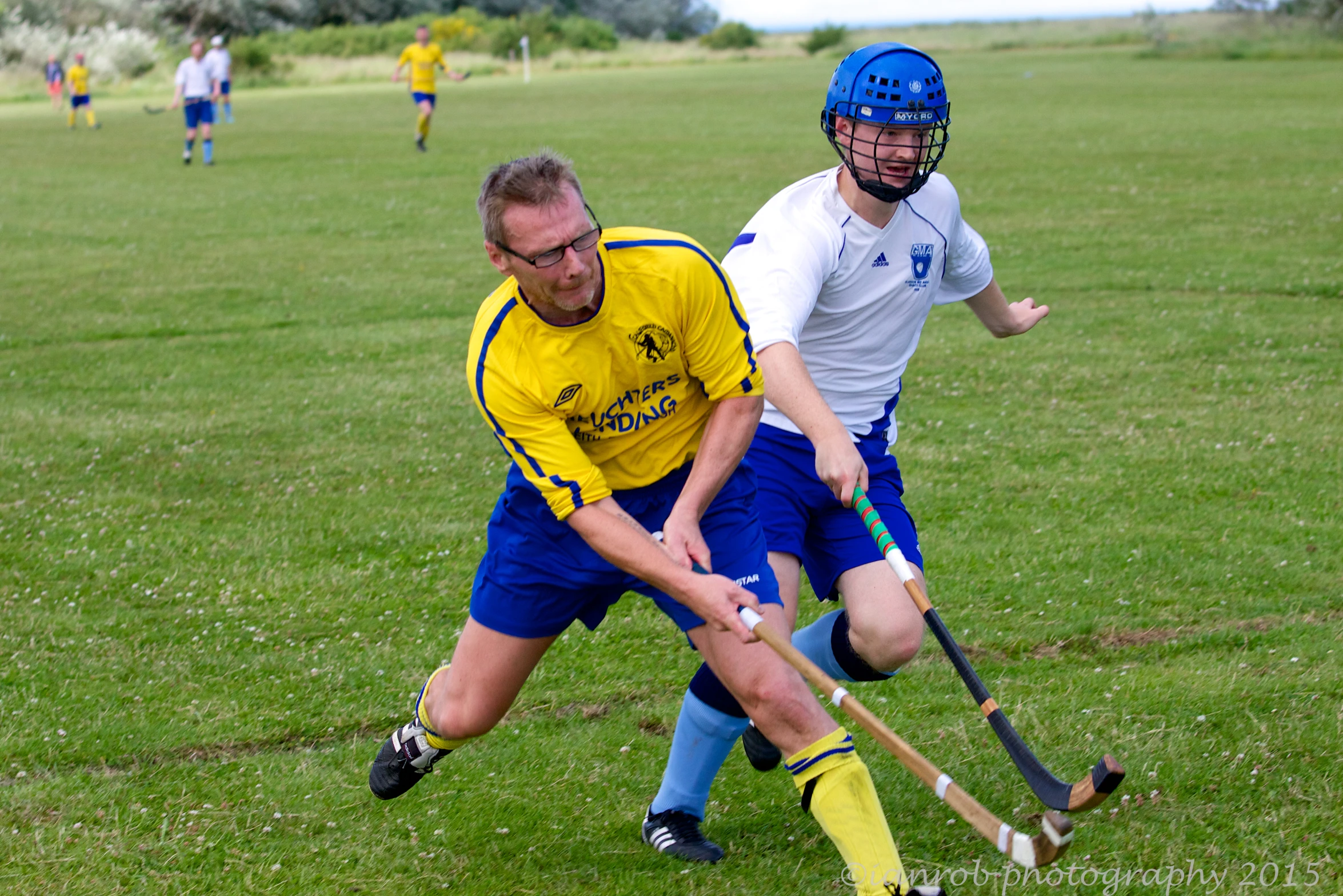 two people on field with a lacrosse ball and a ball in the air