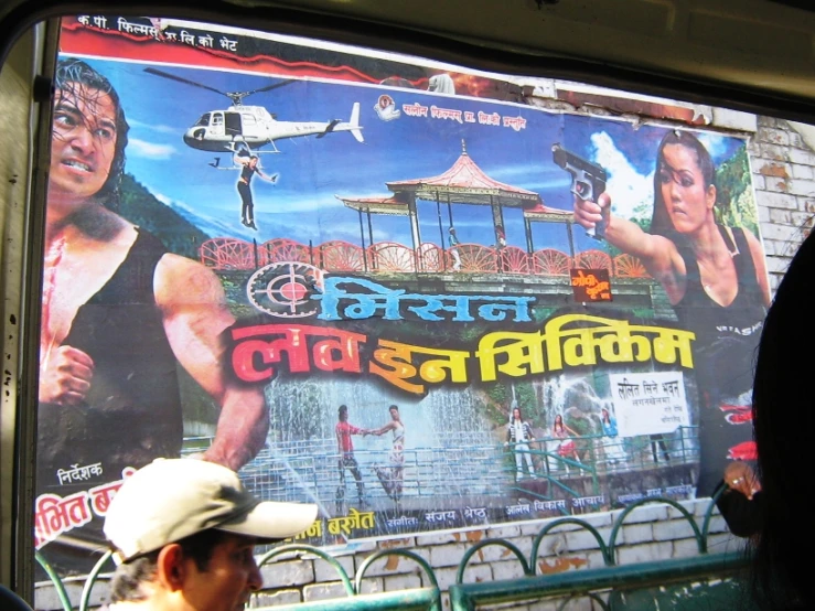 a man in a hat stands near a poster on a bus