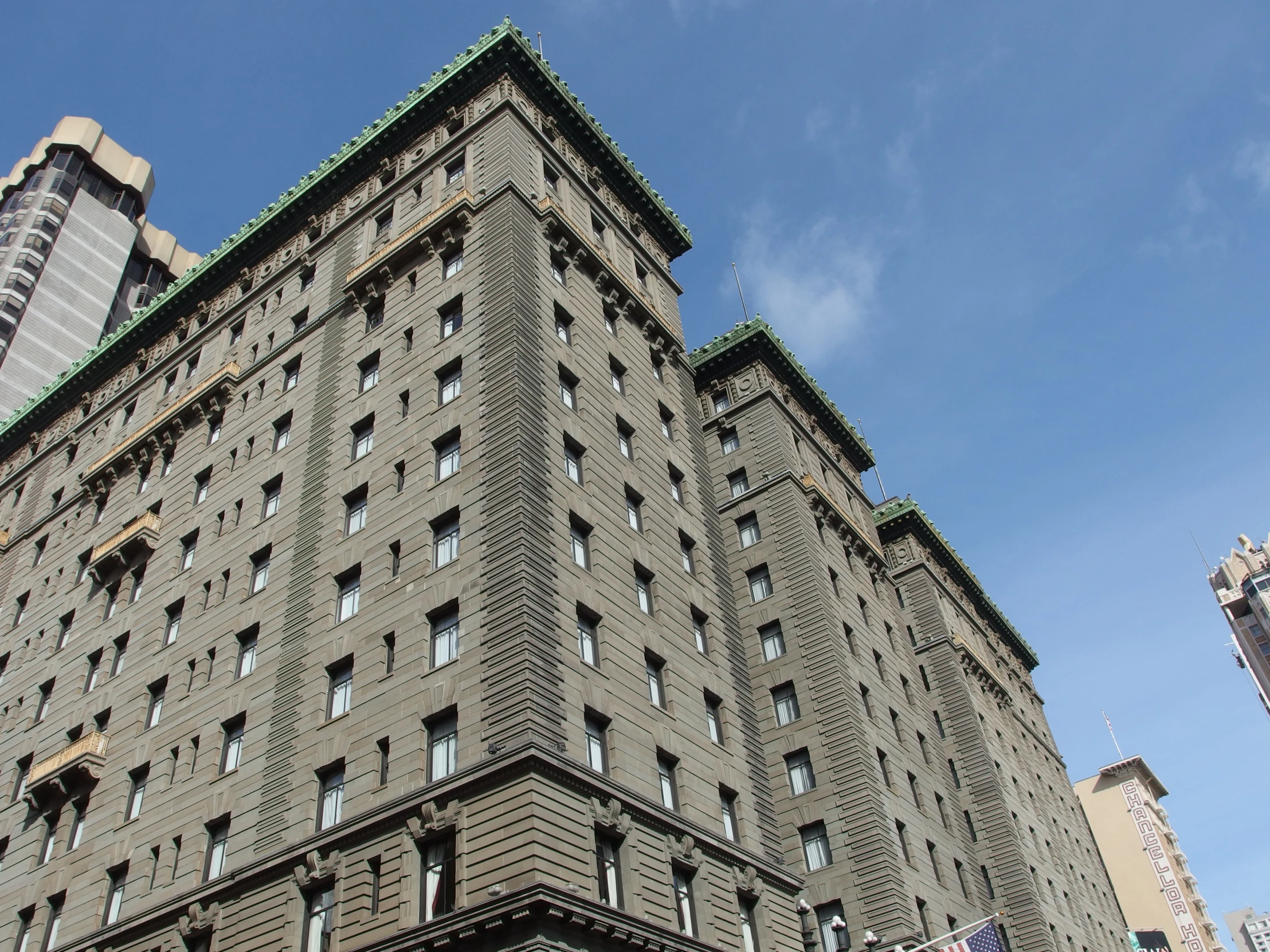 an old, grey building in the city has many windows and one is very tall