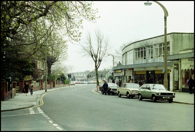 some traffic in a street with buildings and a few people