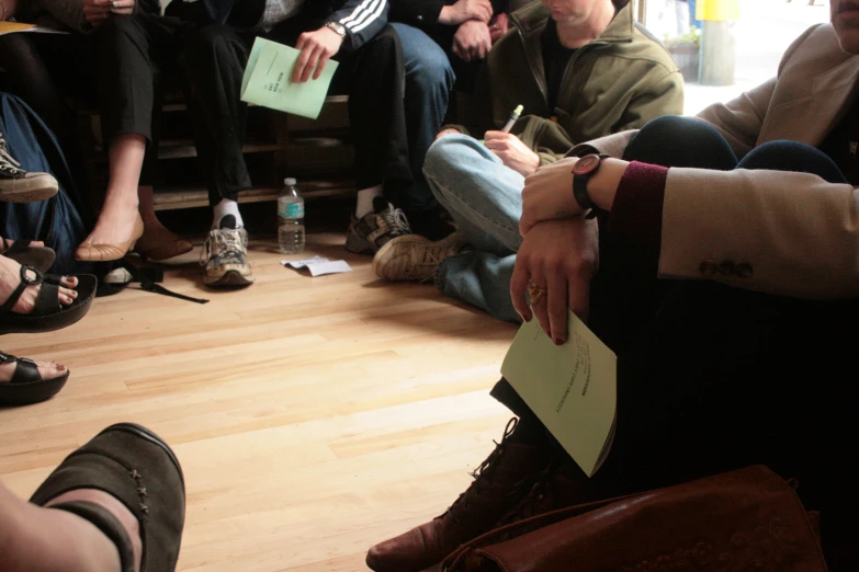 several people sitting down on the floor with notepads