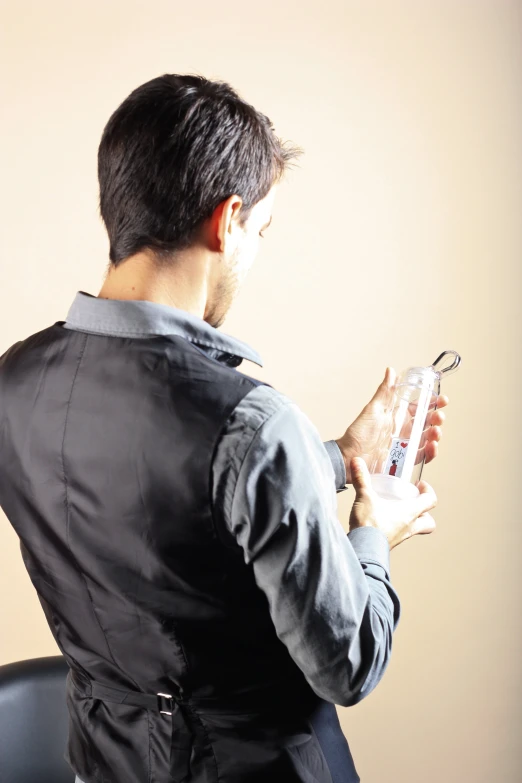 a man in suit sitting down holding onto a clear bottle