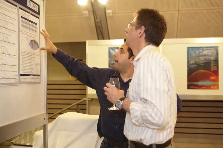 two men standing in front of a white board with drinks