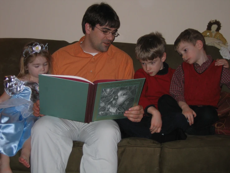 a man reading a book to three little children
