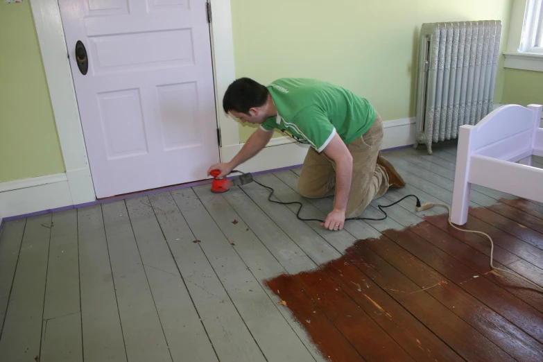 a person sanding a floor with a red power drill