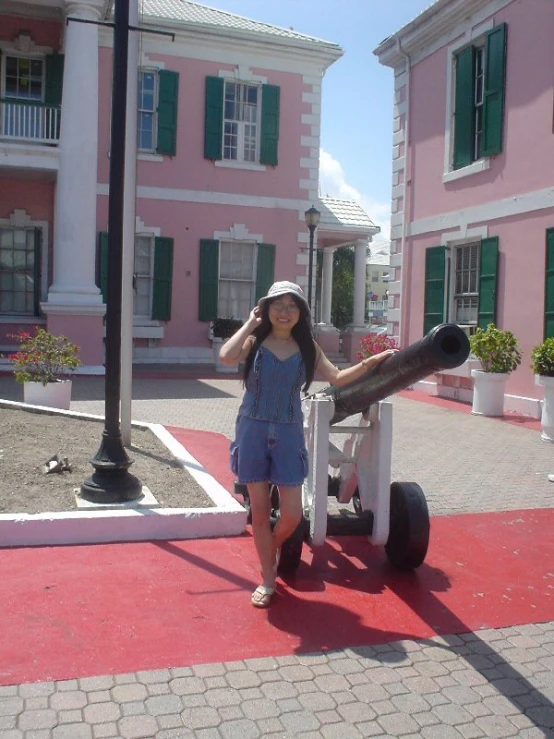 the girl is standing beside an old cannon