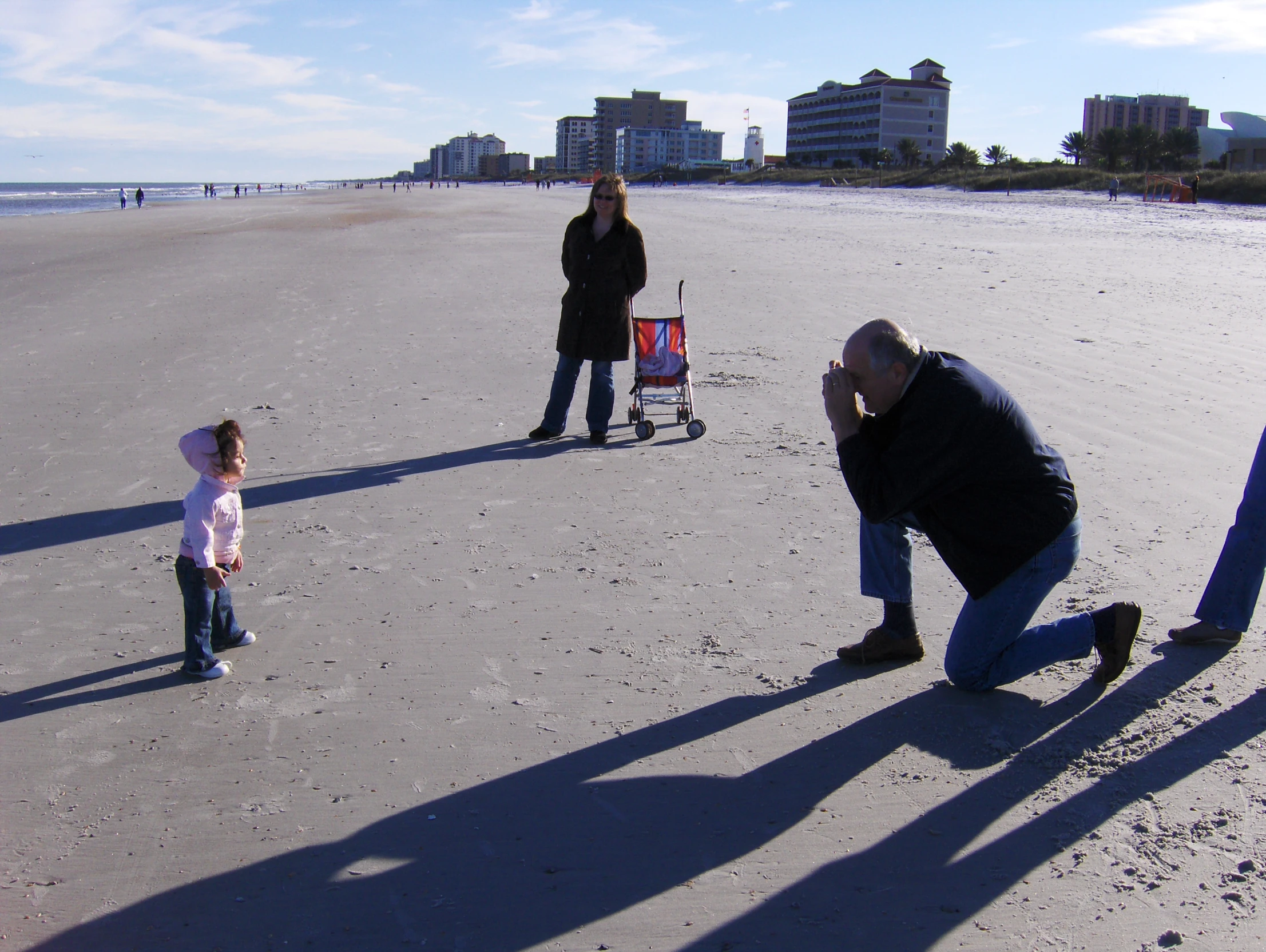 a father and daughter are standing on the beach while the daughter walks toward them