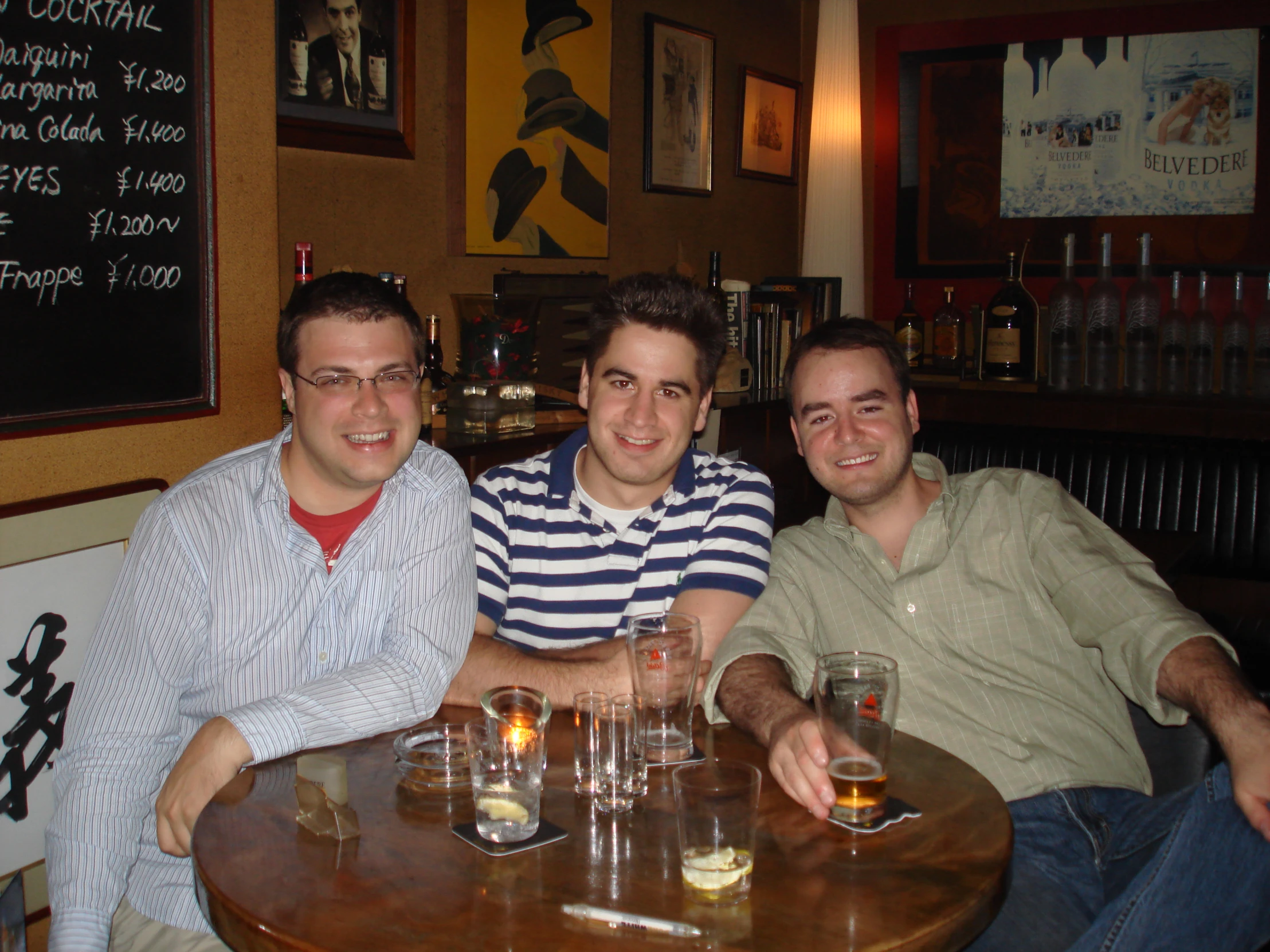 two men sit near each other at a table with beers