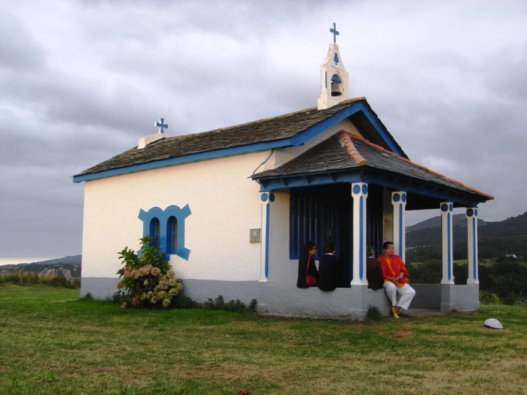 people sitting on the stairs of a small white building