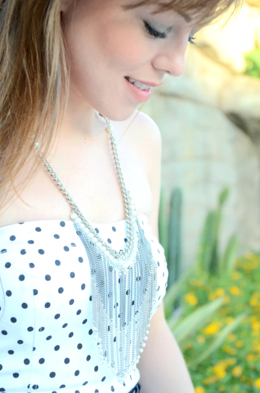 a girl in a polka dotted dress smiles as she holds her cell phone