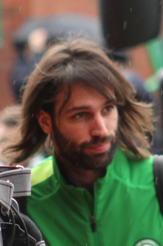 a man with long hair and a green jacket