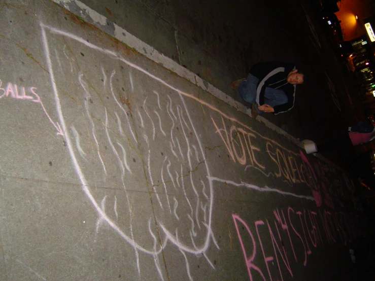 the man is next to a graffitied wall