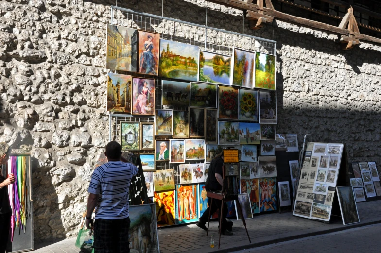 two people standing near a wall with some art on it