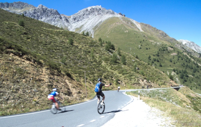 two bicyclists riding down a road in the mountains