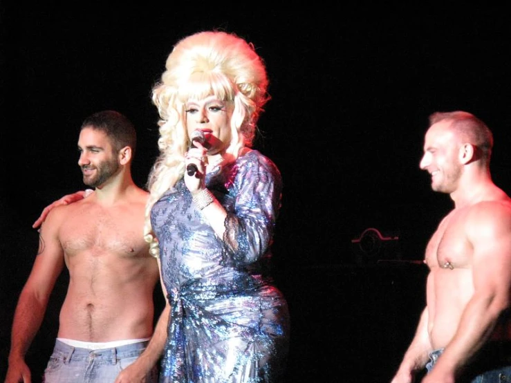 the three men are standing behind lady in shiny clothing