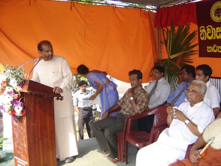 several people are sitting on red chairs at a podium