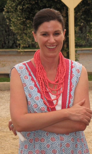 a woman wearing a white and red dress with beads on her neck