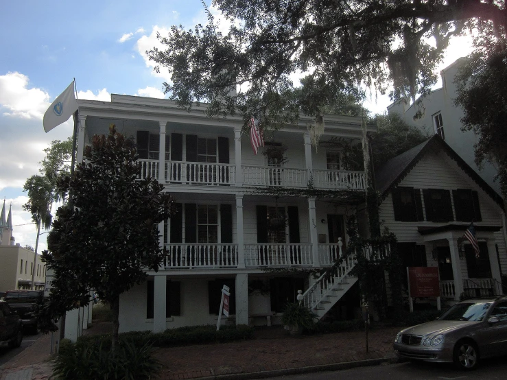 this old house has balconies and some cars parked near it