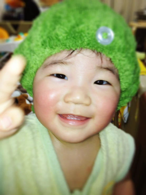 a child in a towel is wearing a green hat