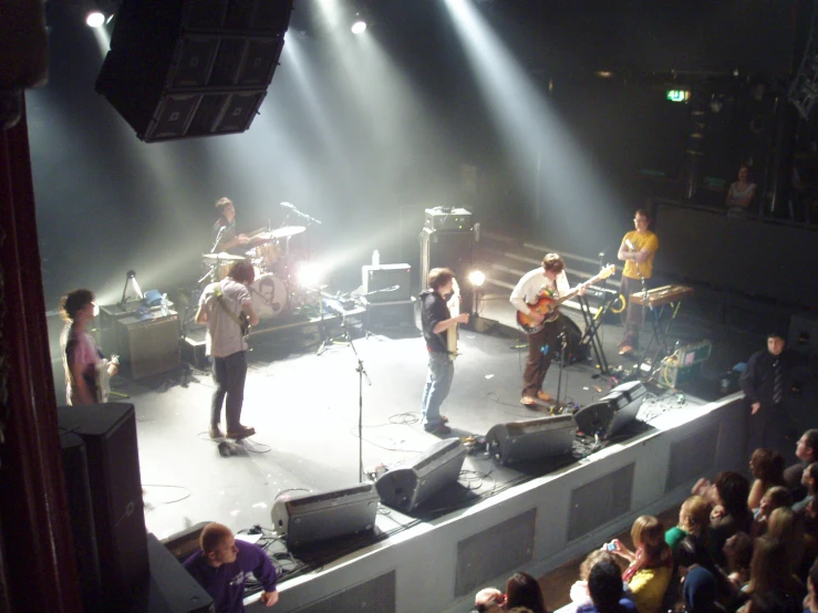 four men singing while playing instruments on a stage